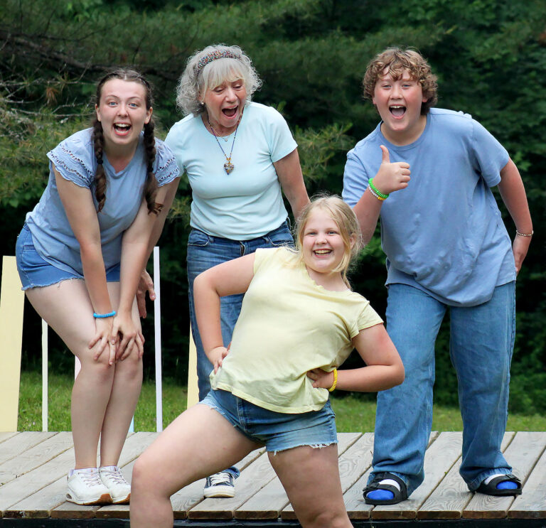 four people standing and smiling on an outdoor stage