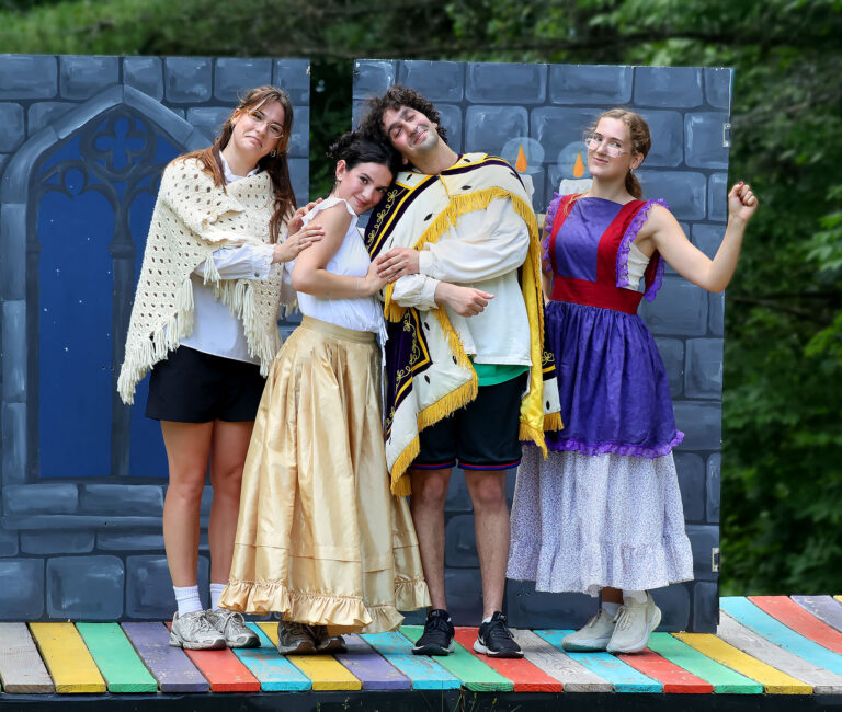 Four people in fairytale costumes standing and smiliing